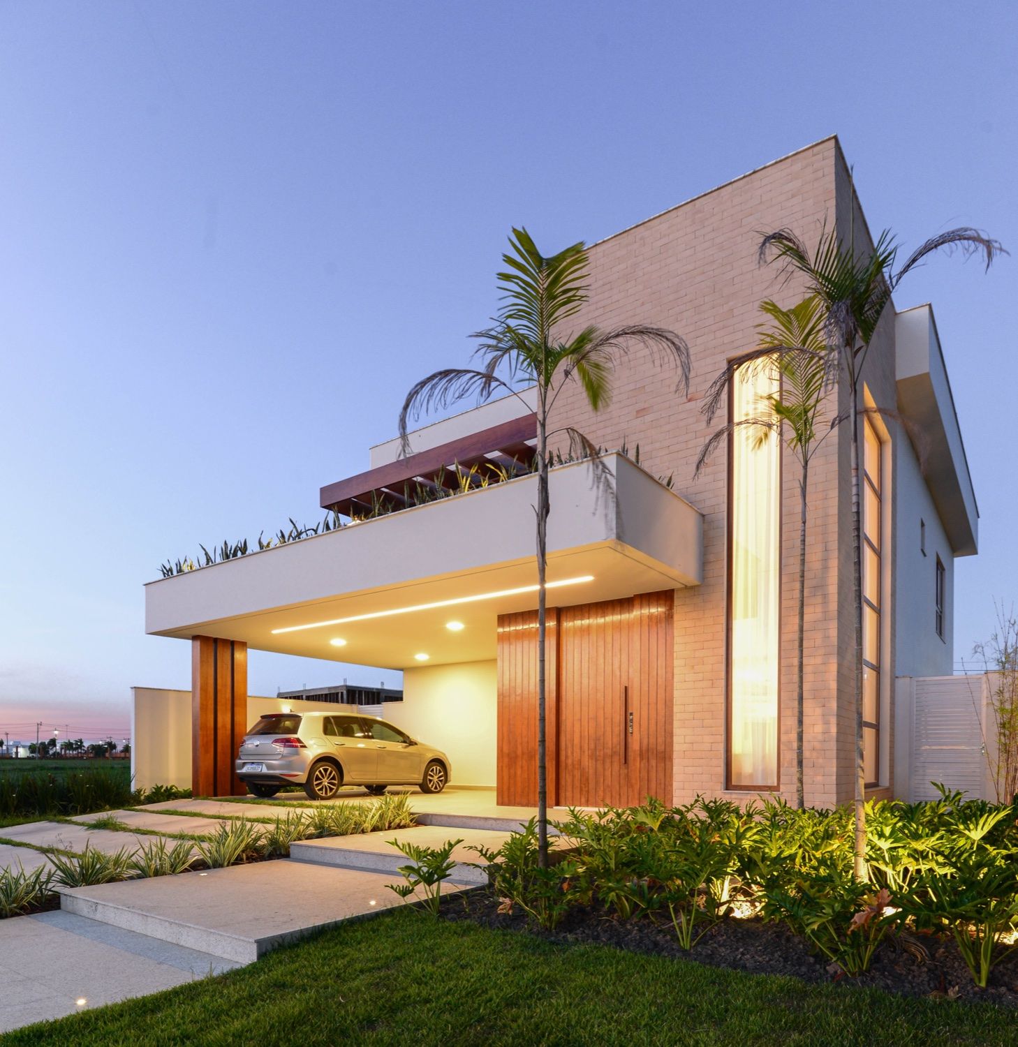 Casa LT — fachada iluminada ao entardecer, residência no condomínio Alphaville